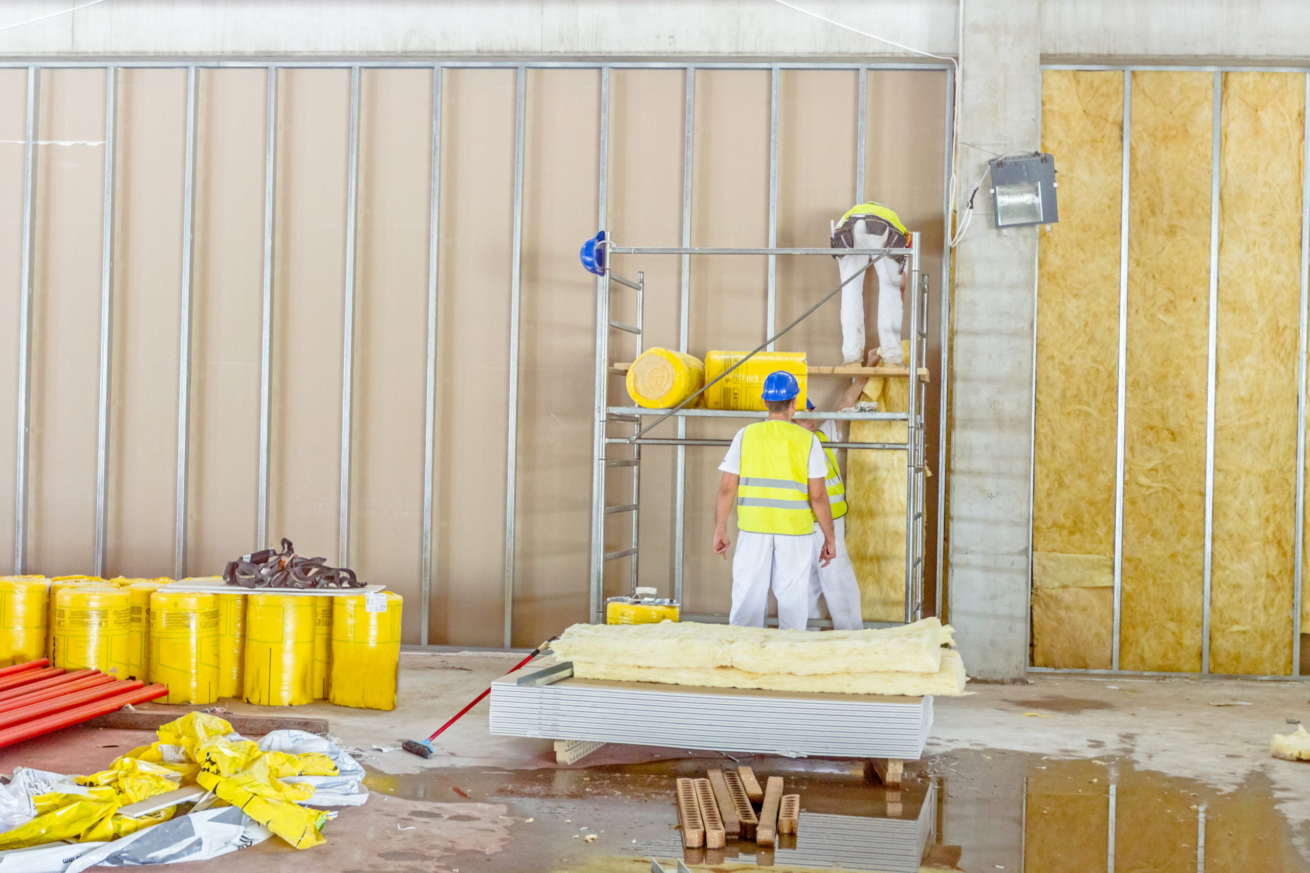 Riggers are working on thermal partition dry wall with mineral wool Zrenjanin, Vojvodina, Serbia – June 29, 2015: Building activities during construction of the large complex shopping mall "AVIV PARK" in Zrenjanin city.